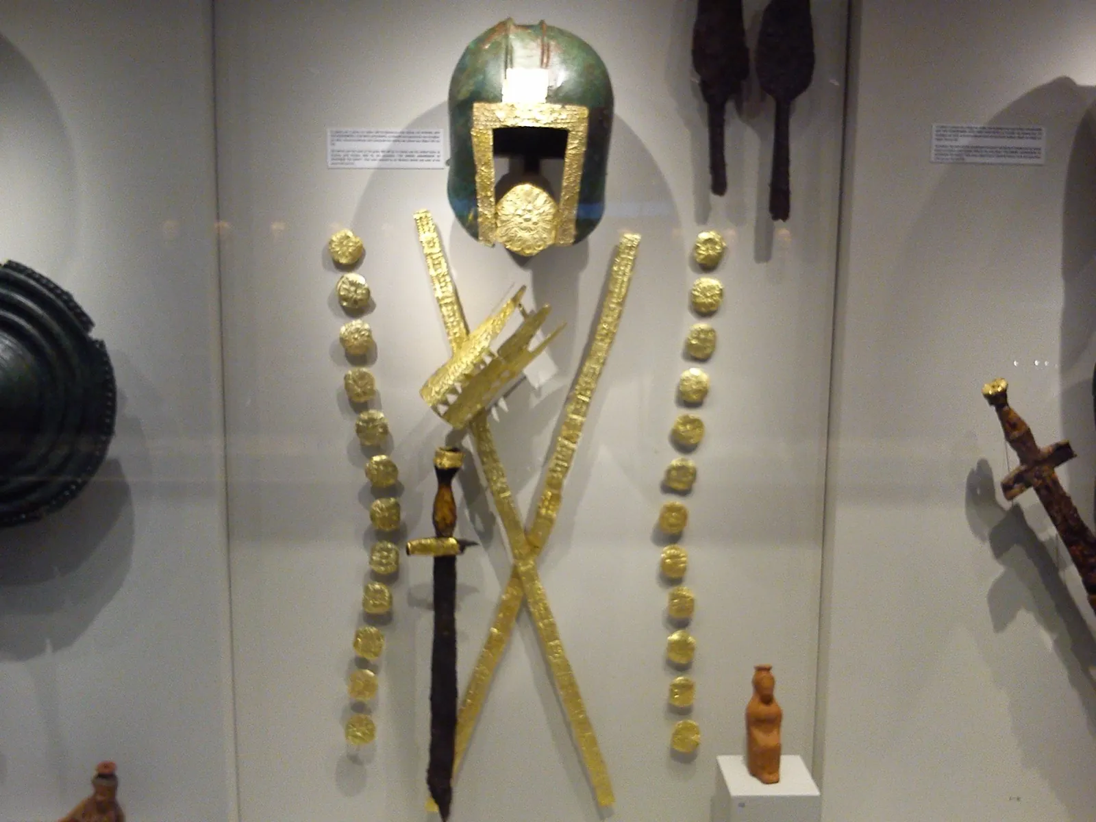 Gold and bronze grave-goods — a helmet, gilded armour, a wreath and a sword — from the royal tombs, displayed at Vergina.